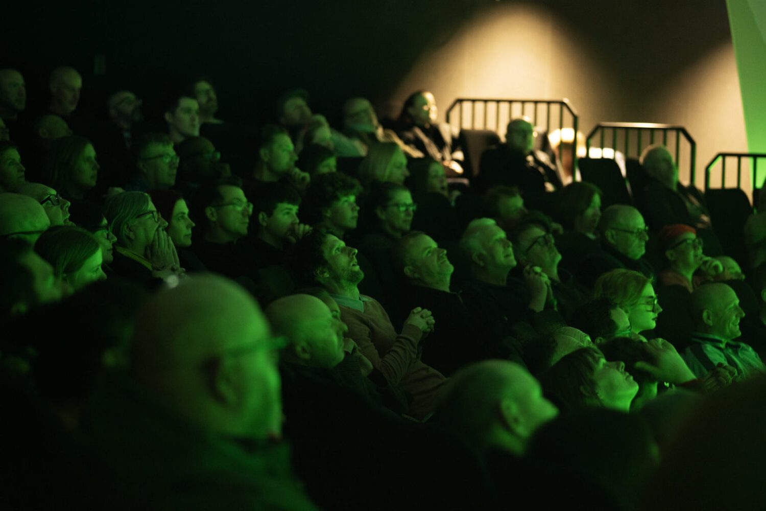 A photo of an audience watching a Dome Show, illuminated in green.