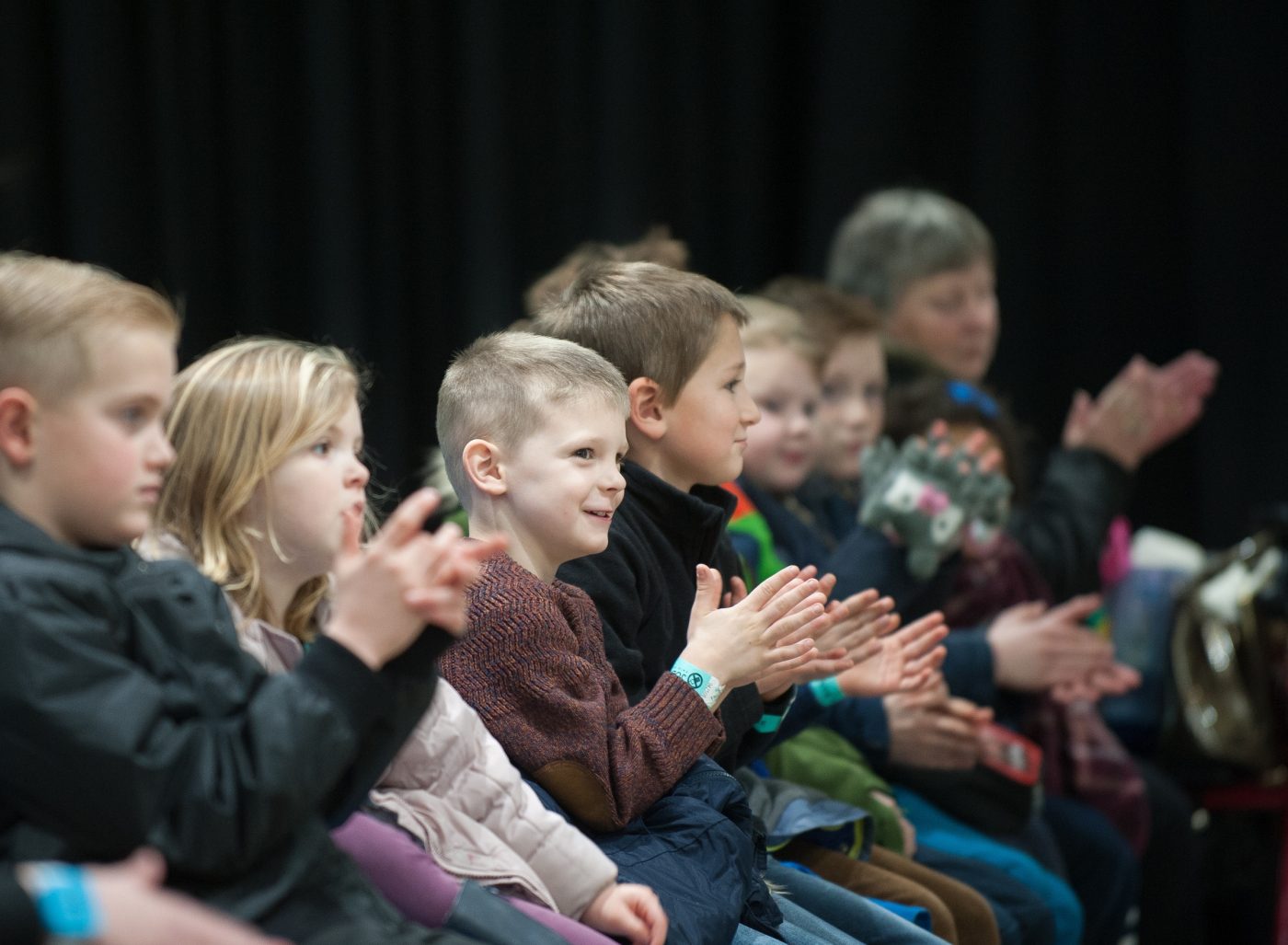 A group of children applaud at a science show.
