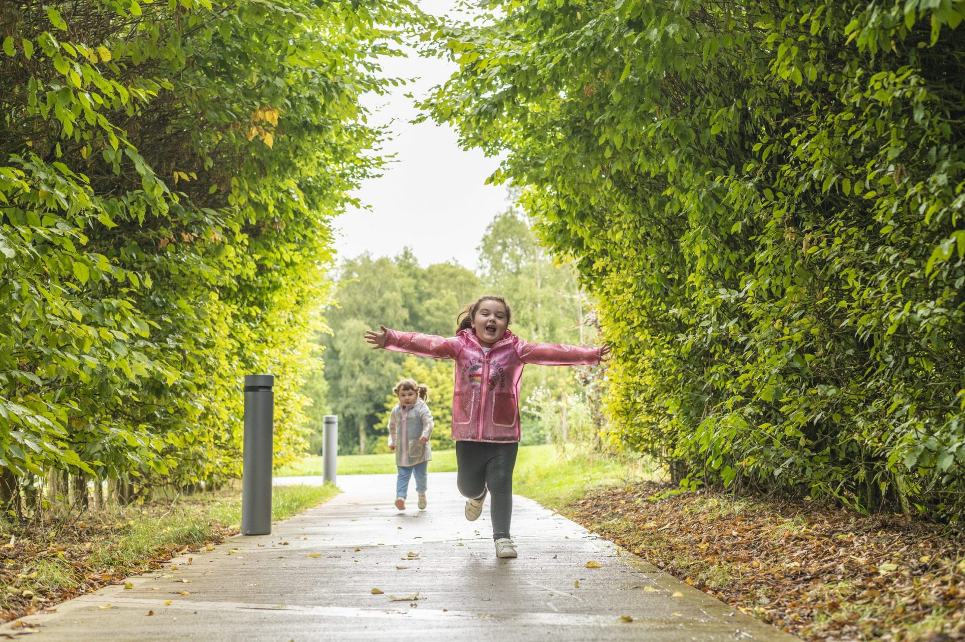 A photo of a little girl running like a spaceship in green gardens.