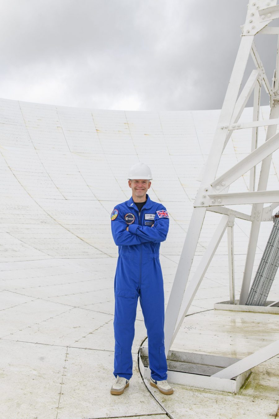 Astronaut reserve John McFall in a hard hat, stood in the Lovell Telescope.