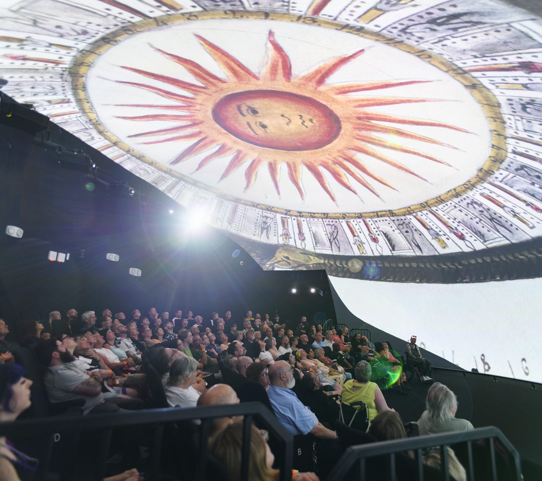 A packed Space Dome audience look up at an illustration of the sun in a new Dome Show.