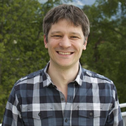 A photo of Professor René Breton, a man wearing a blue and grey plaid shirt standing outside with trees in the background.