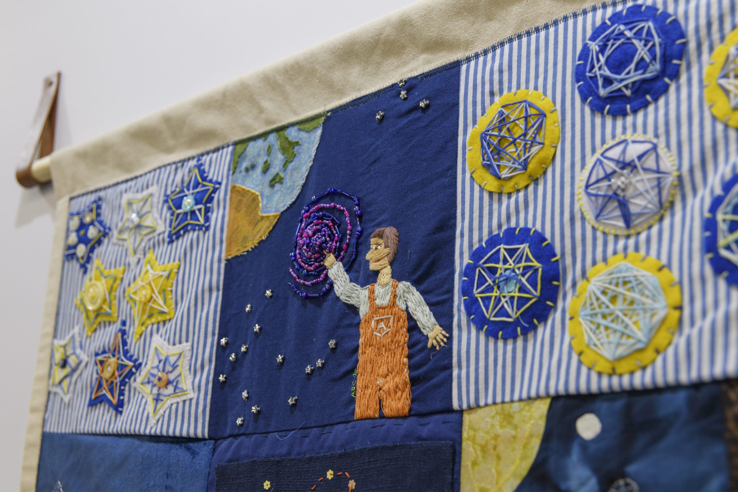 A close-up look at one of the quilts, depicting an observer reaching out to space.
