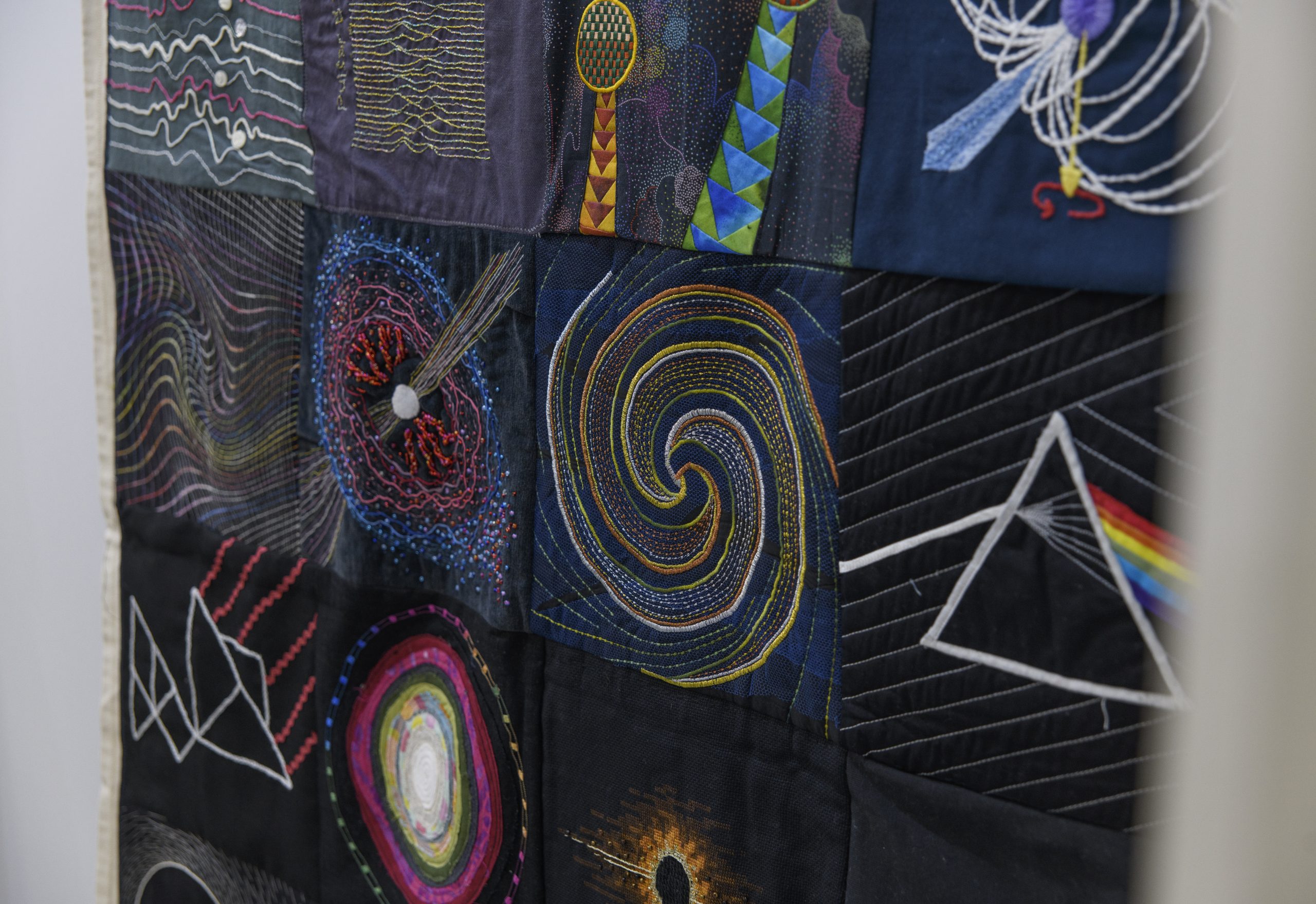 A close-up look at one of the quilts, depicting scientific phenomena and the Dark Side of the Moon album cover.