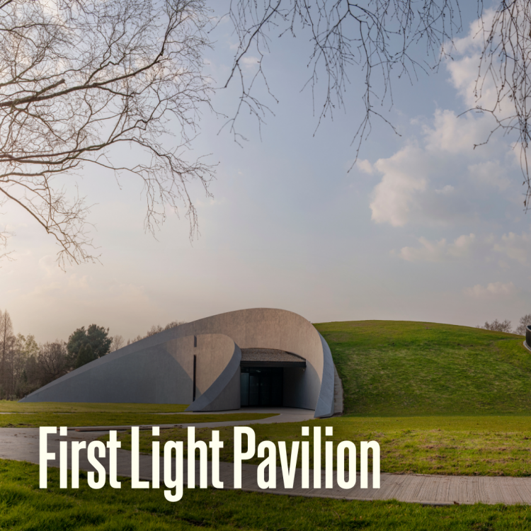 Exterior view of the First Light Pavilion showing its curved, grass-covered structure beneath a partly cloudy sky. The text ‘First Light Pavilion’ appears at the bottom left side of the image.