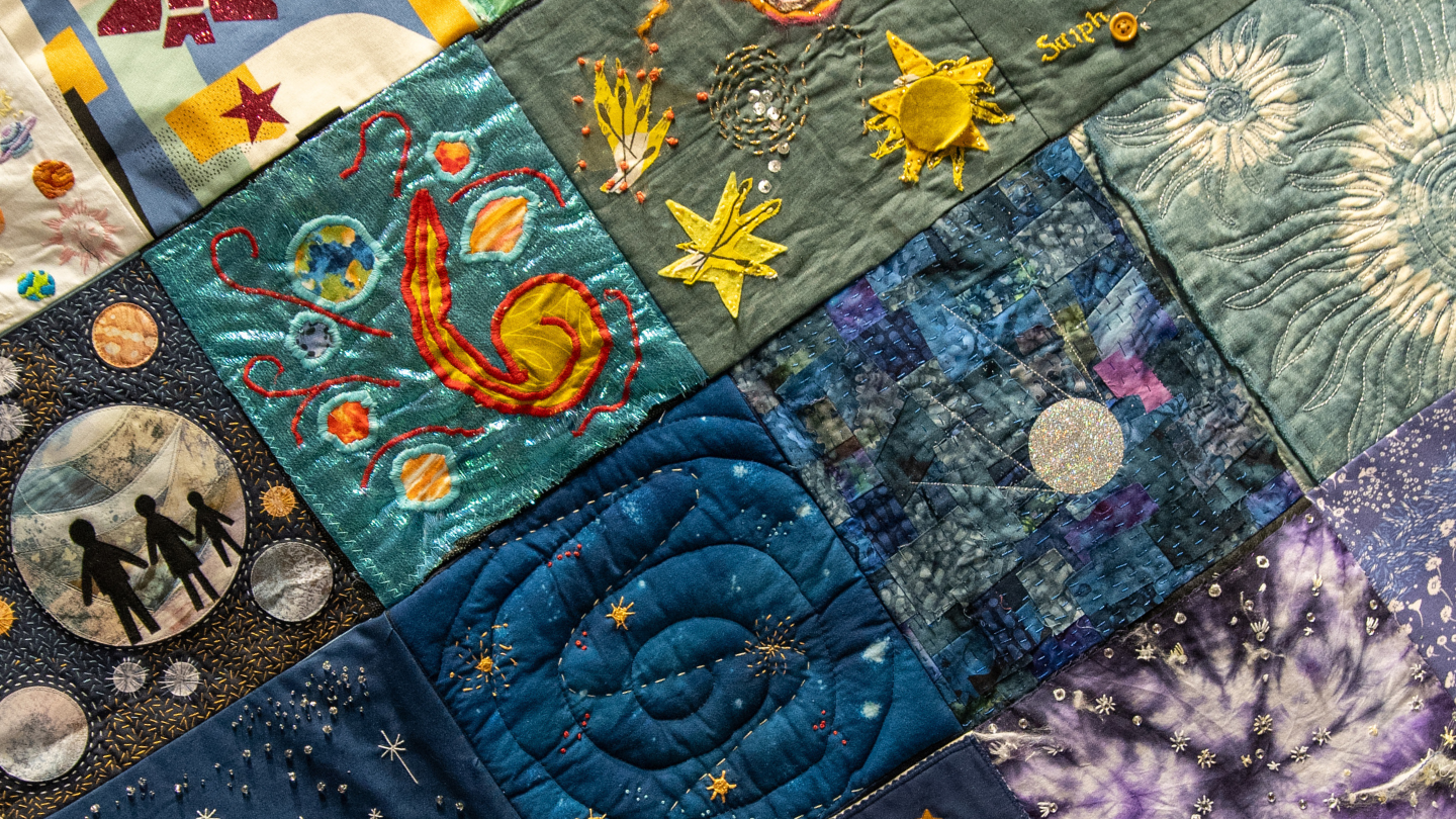 The cosmic thread quilt, depicting colourful patches on space-themed artwork.