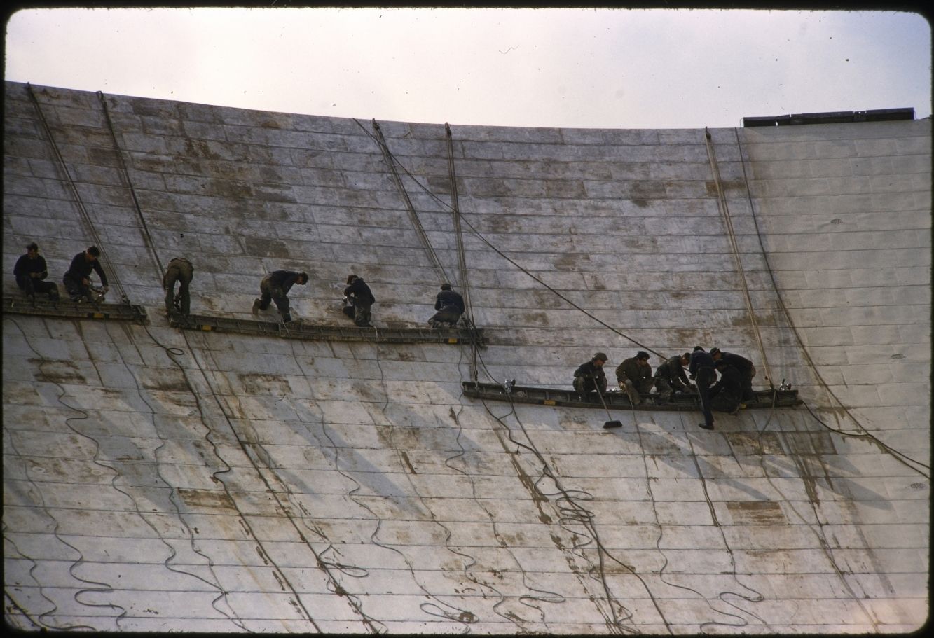A group of workers suspended on the Lovell Telescope, sanding the dish