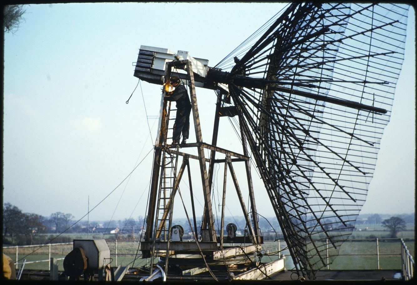 A smaller contraption made of metal, a man stood on a ladder working on the structure
