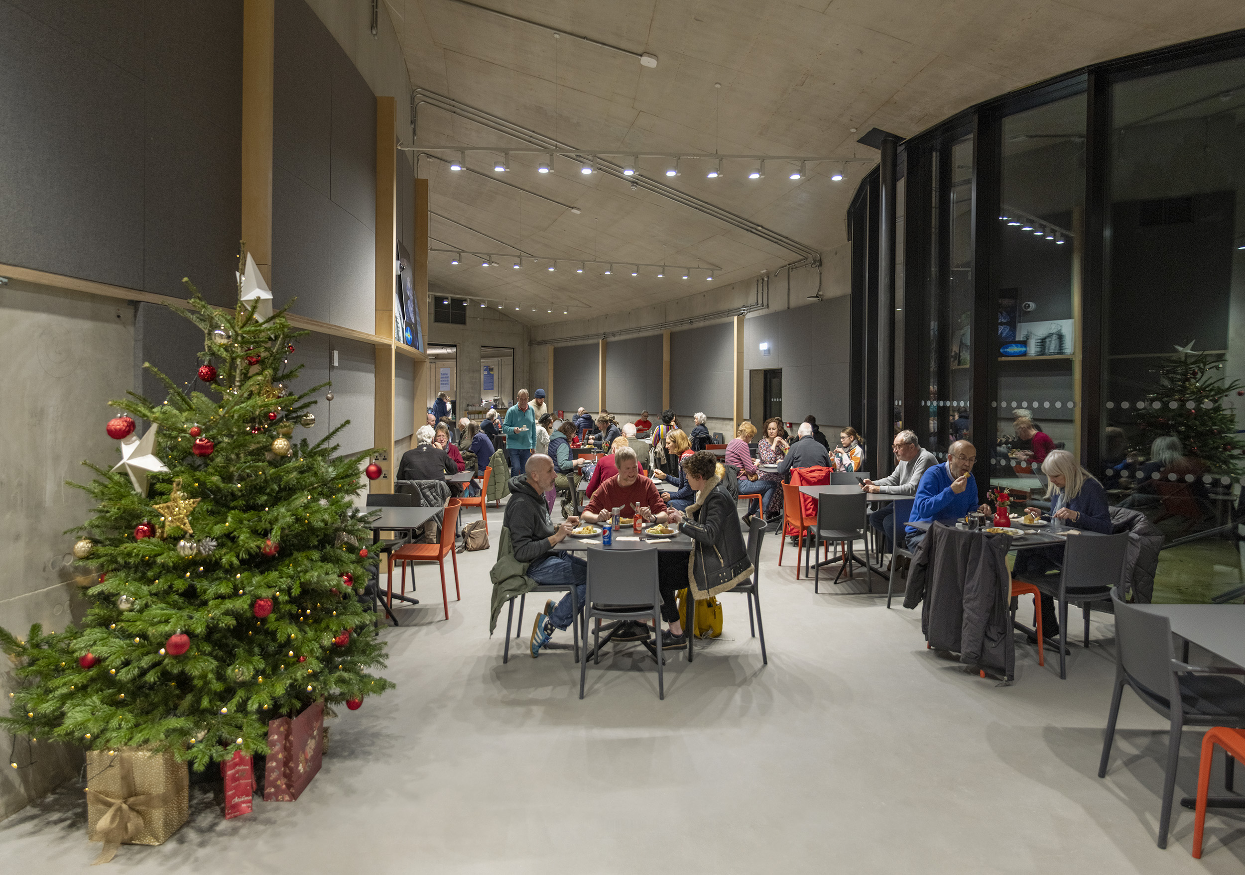 A corporate Christmas evening taking place in the First Light Cafe. Staff eat by a decorative Christmas tree.