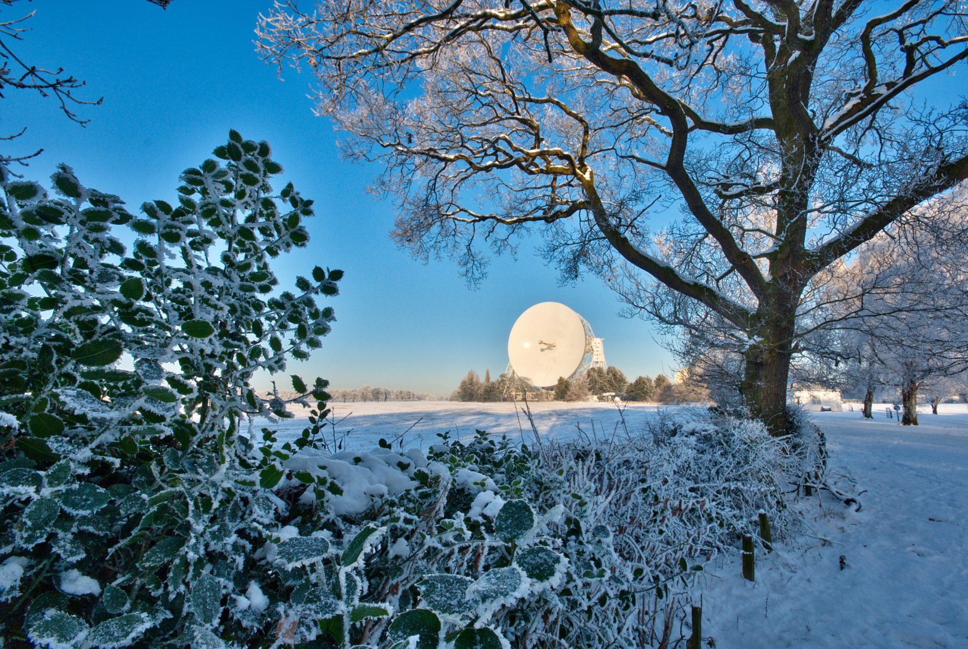 The Lovell Telescope across a snowy field on a bright winter's day.
